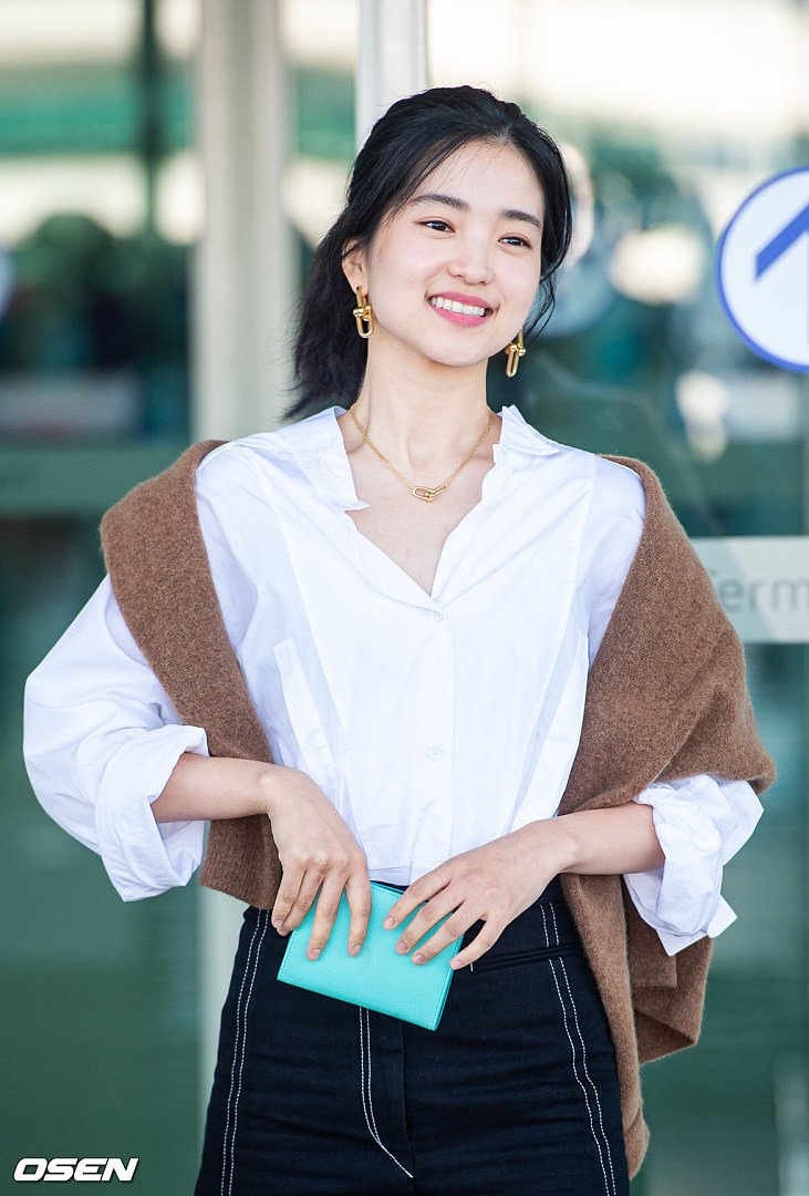 Khi sải bước ở sân bay, Kim Tae Ri luôn ưu tiên sự đơn giản, chẳng hạn như cách cô mặc áo sơ mi trắng kết hợp với quần cạp cao và điểm nhấn là chiếc áo len màu nâu choàng lên vai và mái tóc buộc đuôi ngựa gọn gàng.