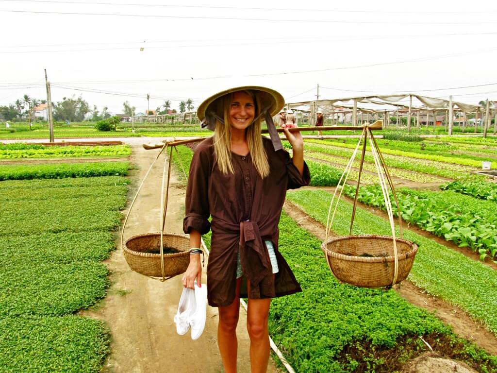 Một du khách trải nghiệm gánh rau ở làng rau Trà Quế. Ảnh danangreview