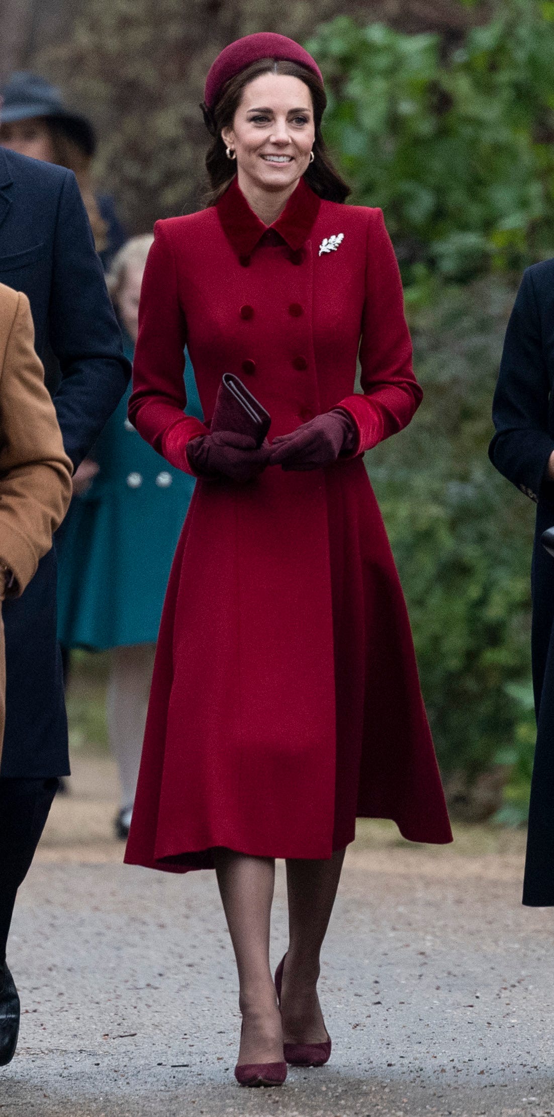 Kate Middleton rạng rỡ trong chiếc áo choàng dài hai hàng cúc, điểm nhấn tay áo, cổ áo bằng nhung màu đỏ sang trọng. Cô nàng thường ưa chuộng phong cách tone-sur-tone.
