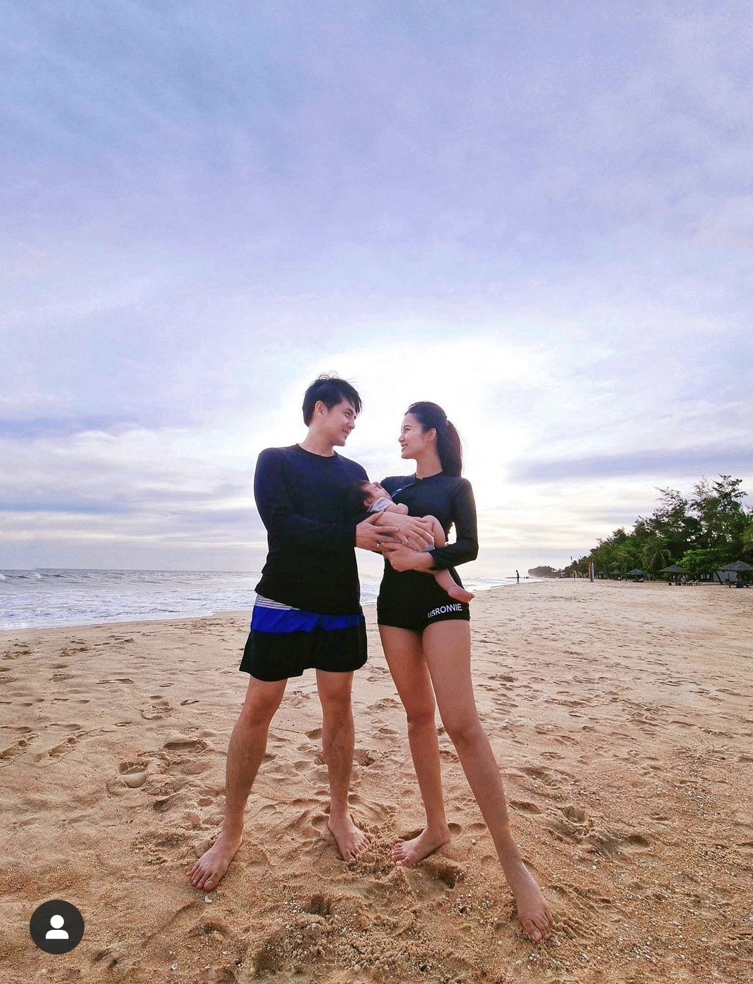 Nữ ca sĩ hạnh phúc bế bé Winnie chụp ảnh cùng chồng trên bãi biển Phú Quốc. Ông Cao Thắng cũng chọn áo dài tay màu đen giống bà xã.
