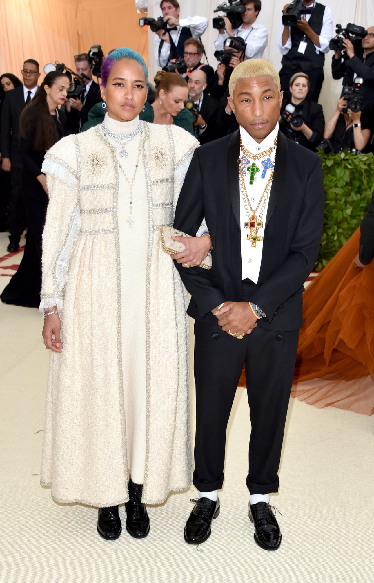Pharrell Williams hộ tống vợ tới Met Gala. Nam ca sĩ mặc suit đen đơn giản, gây ấn tượng bằng phụ kiện hình thập giá nạm đá nhiều màu.