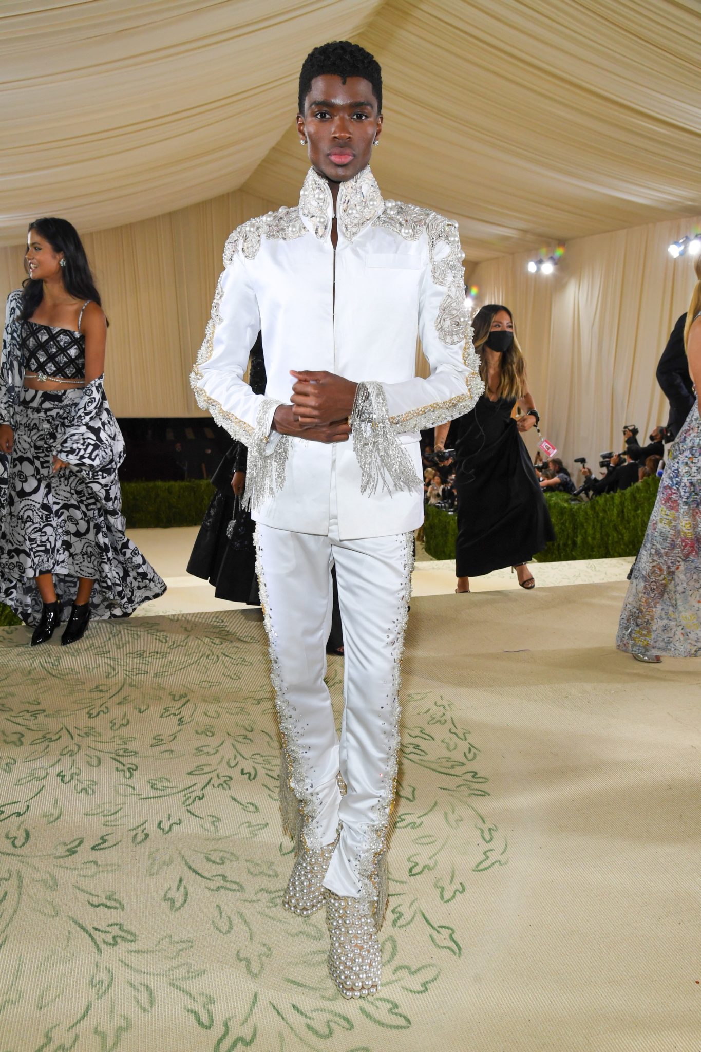 Nam người mẫu Alton Mason thể hiện khí chất vương giả, sang trọng với thiết kế suit trắng của Theophilo. Nổi bật nhất là hàng ngọc trai được đính kết hai bên cầu vai và đôi giày bằng ngọc trai độc đáo.