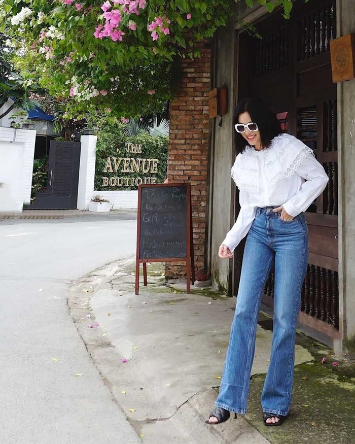 Tú Hảo nữ tính khi kết hợp áo blouse trắng với quần jeans ống loe và giày cao gót.