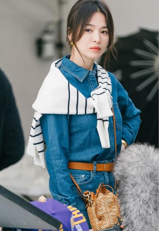 Tận dụng chiếc áo kẻ sọc trở thành phụ kiện như khăn choàng, Song Hye Kyo gợi ý set đồ năng động, tôn dáng với jumpsuit jeans, phụ kiện da nâu.