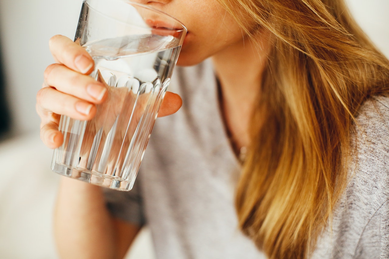 Uống đủ nước từng ngụm nhỏ để cung cấp nước cho da và cơ thể.