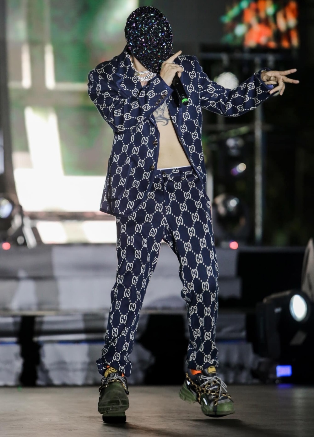 Binz diện bộ suit Gucci Jacquard để ngực trần, kết hợp với giày sneaker Gucci Flashtrek chunky. Chiếc mặt nạ tông màu xanh lấp lánh khá lạ mắt.
