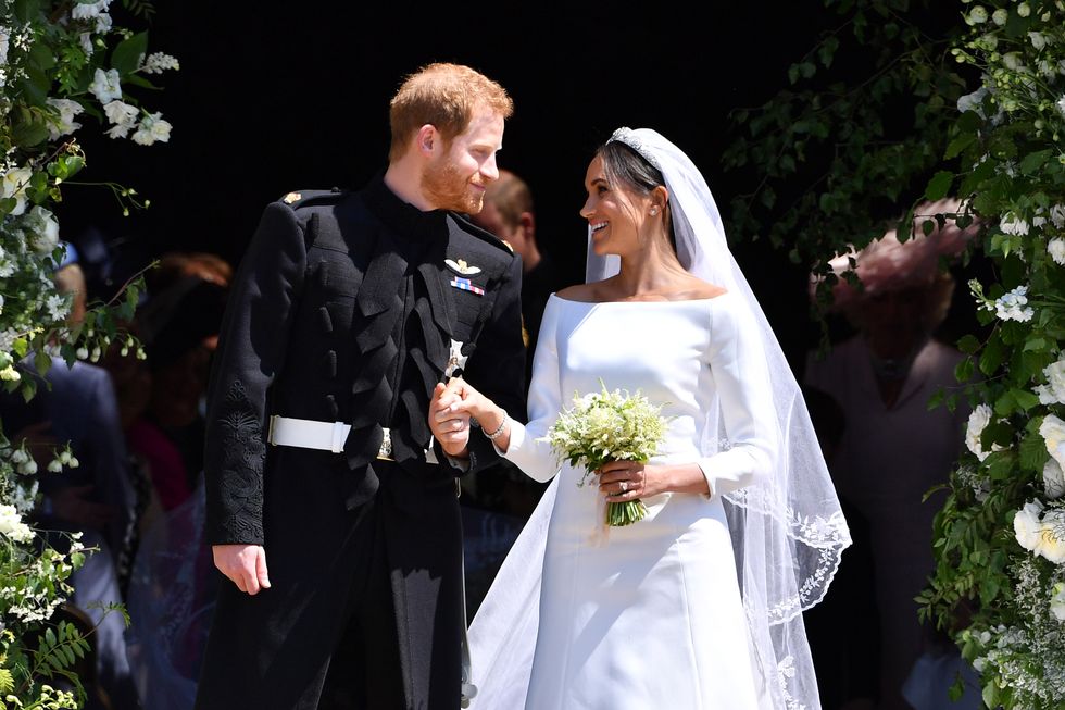 Hoàng tử Harry và Meghan, Nữ công tước xứ Sussex diện váy cưới vải taffeta cười rạng rỡ, bước ra từ nhà nguyện sau khi kết hôn vào năm 2018.