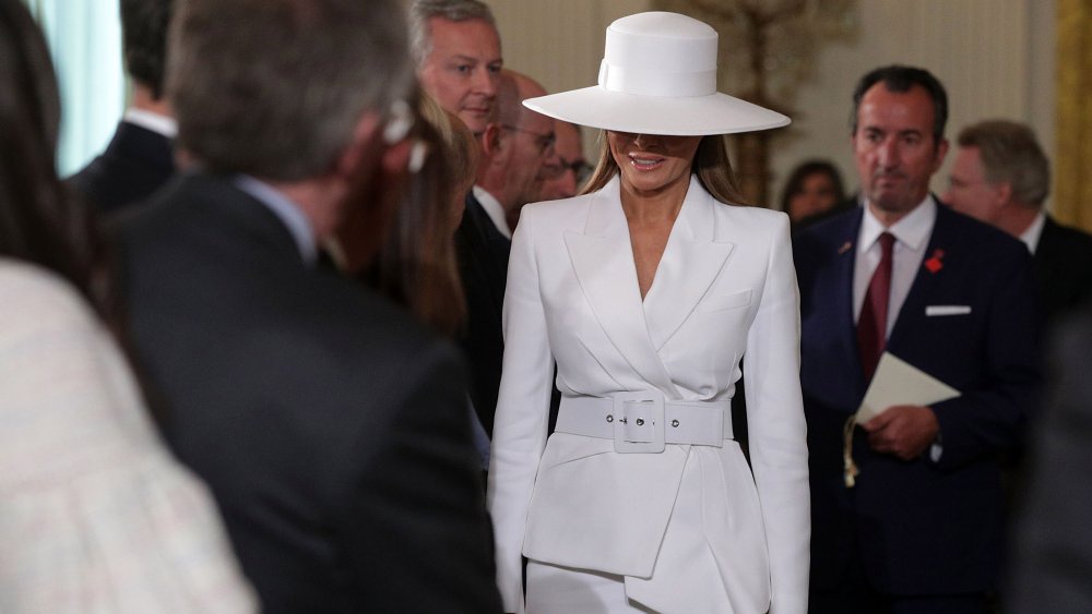 Bà Trump diện một bộ suit màu trắng từ thương hiệu Michael Kors có giá 2195 USD. Bà hoàn thiện bộ trang phục với đôi giày Christian Louboutin giá 745 USD