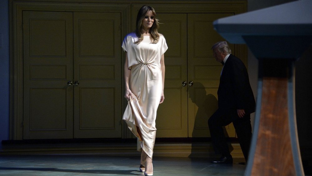 Khi tham dự buổi dạ tiệc hàng năm tại nhà hát Ford vào đầu tháng 6, bà Trump đã lựa chọn váy lụa vàng có giá 2.595 USD của nhà thiết kế Monique Lhuillier. Chiếc váy có đường xếp nếp tinh tế ở lưng. Bà hoàn thiện vẻ ngoài với đôi giày cao gót 660 USD của Manolo Blahnik