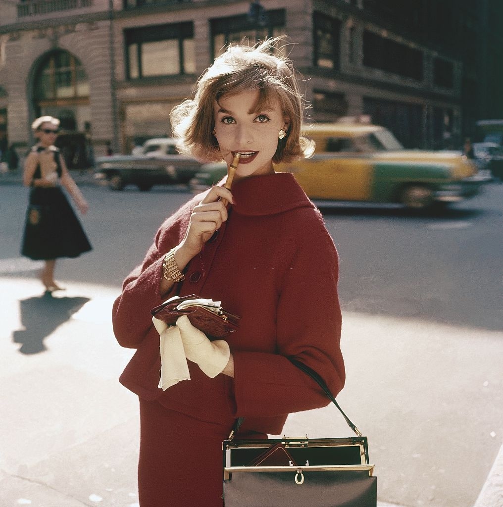 Một người mẫu nữ tạo dáng cho một bộ ảnh của tạp chí Glamour số đăng vào Giáng sinh 1957. Cô diện một bộ suit đồng màu, tay đeo găng trắng, một phong cách thời trang chịu sự ảnh hưởng của công nương Grace Kelly.