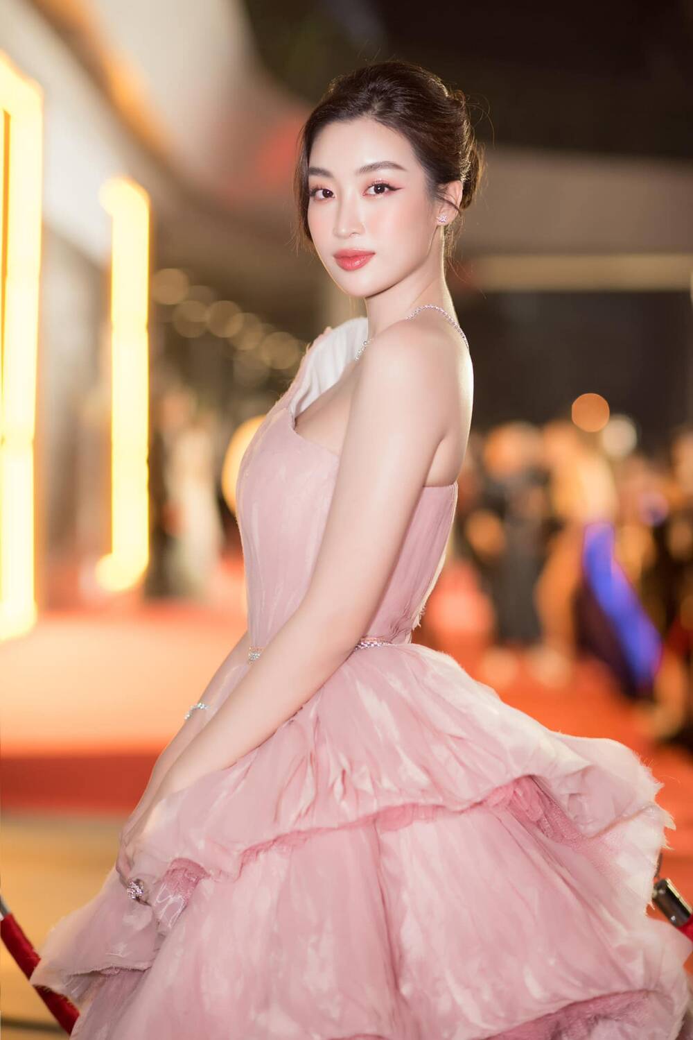 Cô chọn một thiết kế đầm lệch vai của NTK Minh Tuấn. Chiếc váy màu hồng pastel giúp tôn lên làn da trắng trẻo của Hoa hậu
