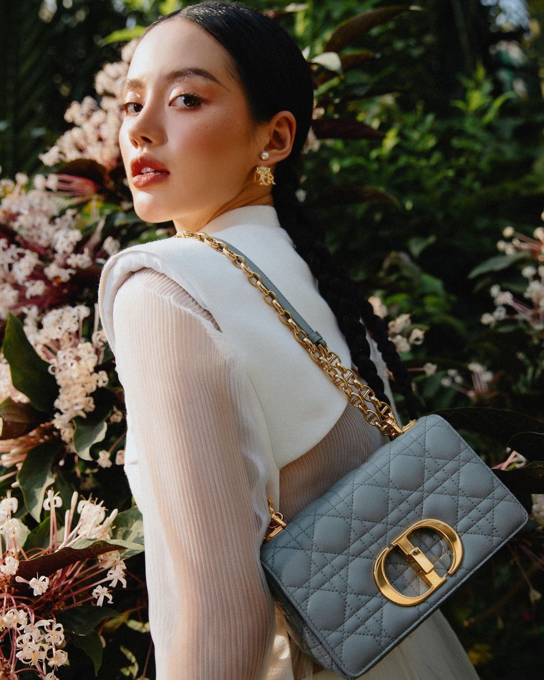 Cô Em Trendy Khánh Linh giữ đúng tinh thần của nhà mốt Paris: Thanh lịch và yêu hoa. Chiếc túi Dior Caro đắt đỏ vô cùng nổi bật trên nền trang phục trắng của Khánh Linh.