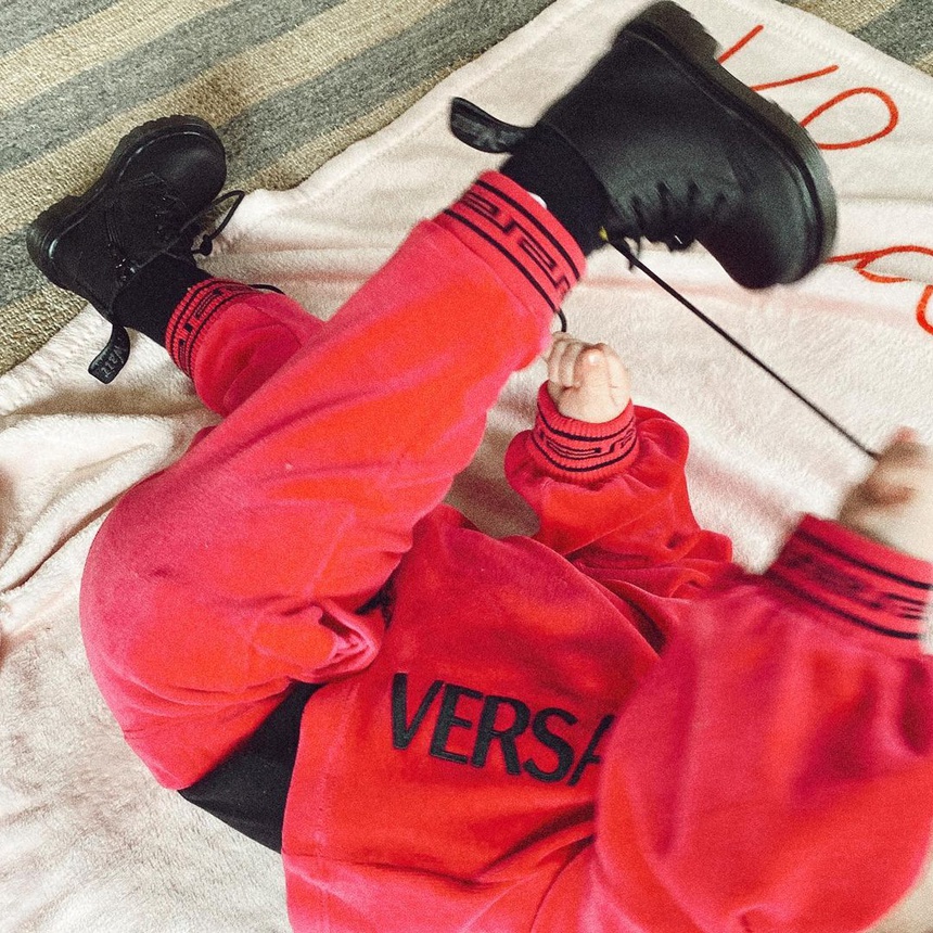 Sáng ngày hôm nay, Gigi Hadid đã đăng tải hình ảnh cô nhóc Khai đang đùa nghịch trong bộ đồ bằng nỉ đỏ của Versace. Cô bé đi đôi boots của Dr. Martens