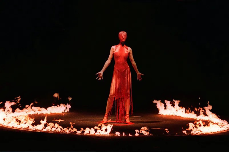 BST mang tên Joan of Arc, người mẫu mặc đồ đỏ và trình diễn giữa một vòng tròn lửa.