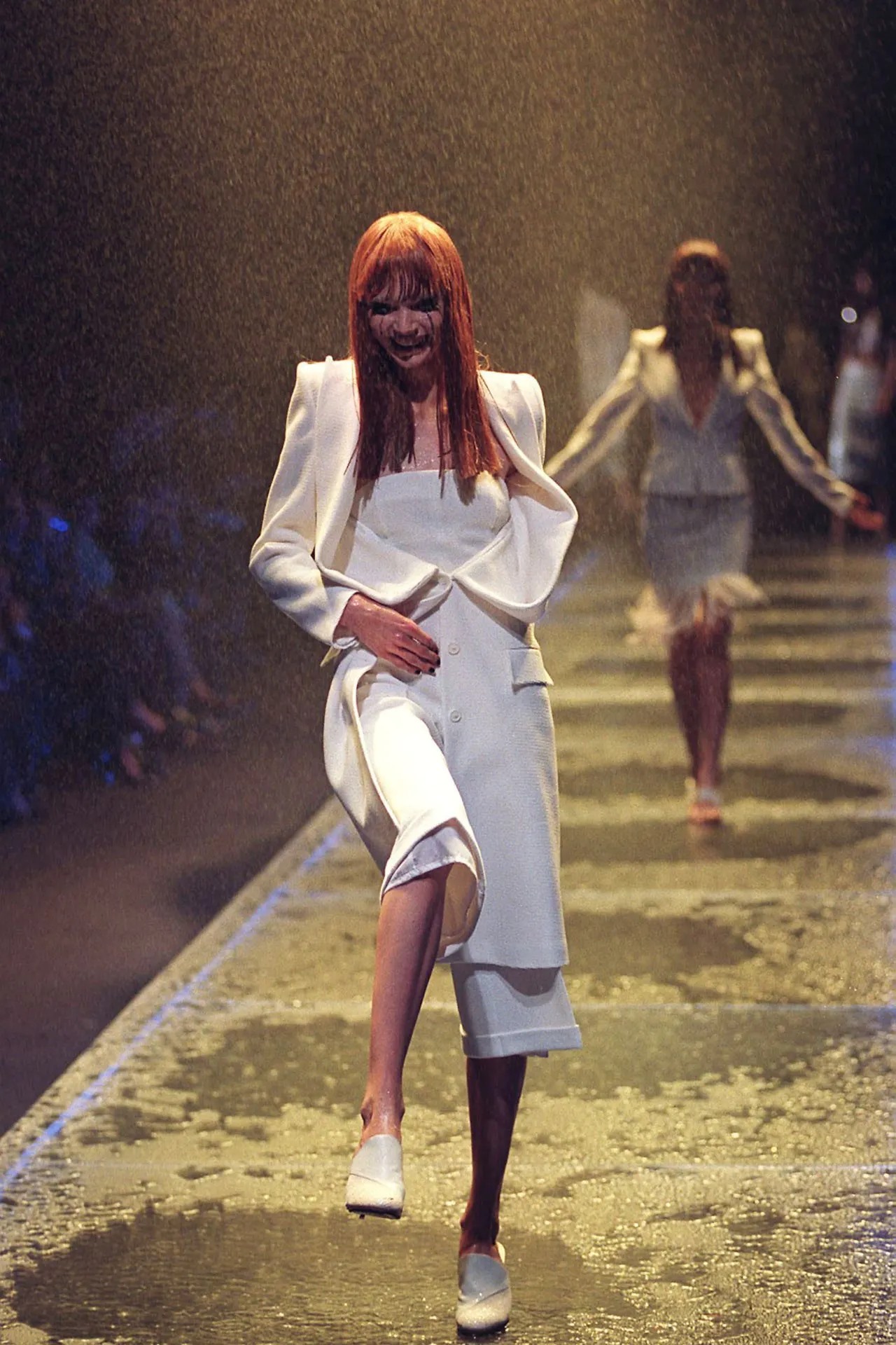 Các người mẫu mặc đồ trắng và sải bước dưới cơn mưa vàng.