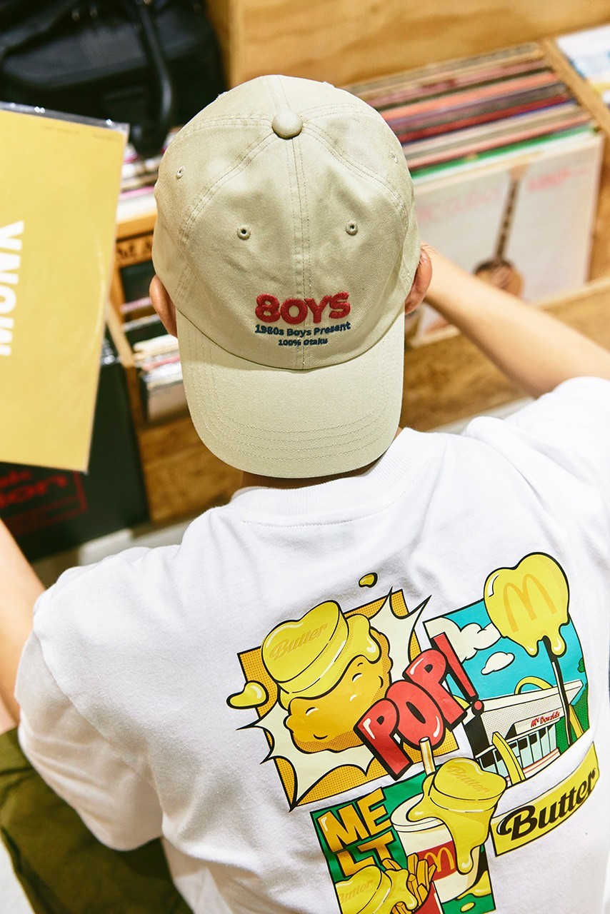 Cận cảnh một thiết kế áo phông và mũ trong BST capsule của BTS x McDonalds. Những hình vẽ vui nhộn đậm chất mùa hè.