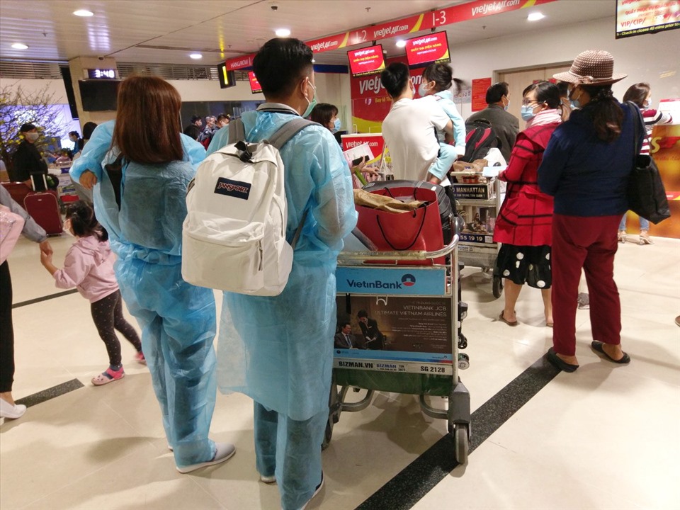 Một gia đình mặc đồ bảo vệ chờ làm thủ tục lên máy bay ở sân bay Tân Sơn Nhất.Ảnh: Báo Lao động