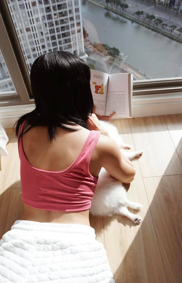 Tú Hảo nằm bên khung cửa đón nắng, vừa ôm thú cưng vừa đọc sách. Trong những ngày nghỉ dịch, cô vẫn chăm chỉ tập luyện để giữ vóc dáng gọn gàng.