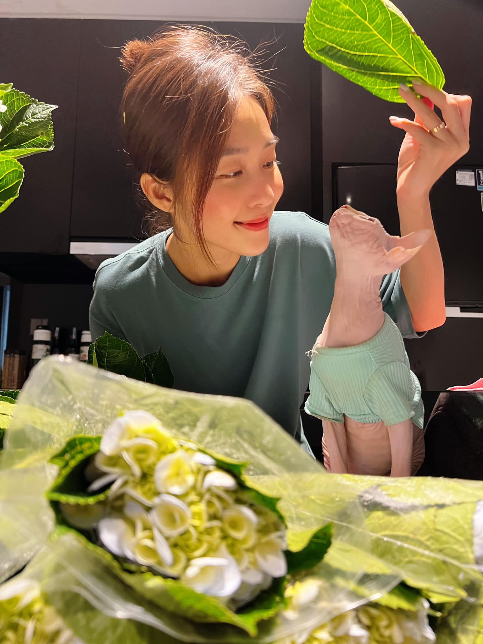 Khả Ngân cắm hoa bên mèo cưng. Nữ diễn viên hiện đang ở Hà Nội để hoàn thành bộ phim '11 tháng 5 ngày'. Vai nữ chính Nhi của Khả Ngân nhận được nhiều lời khen của khán giả nhờ tính cách lém lỉnh, đáng yêu.