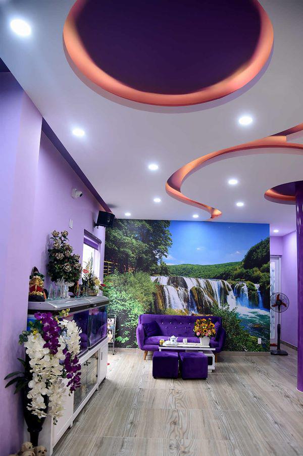 Bộ sofa màu tím được đặt bên cạnh bức tranh thác nước lớn ở phòng khách cho không gian thư giãn.