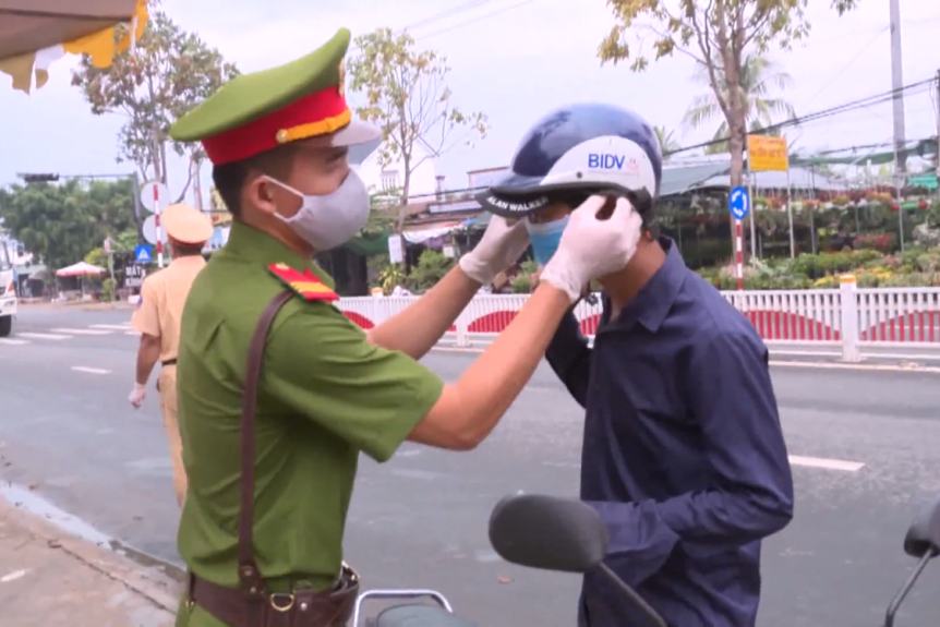 Hình ảnh một cảnh sát Việt Nam đeo khẩu trang cho người đi xe máy