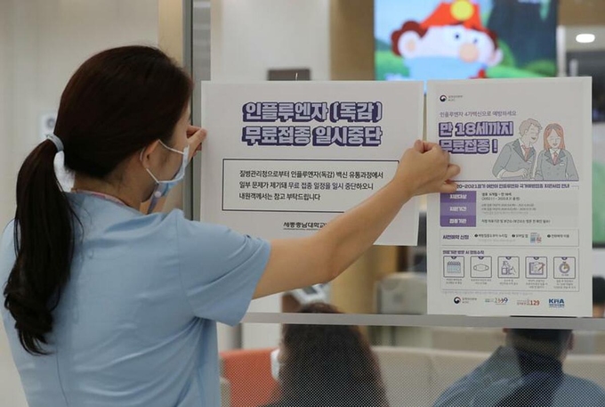 Một nhân viên y tế dán thông báo tạm dừng tiêm phòng cúm ở bệnh viện tại Sejong, ngày 22/9. Ảnh: Reuters
