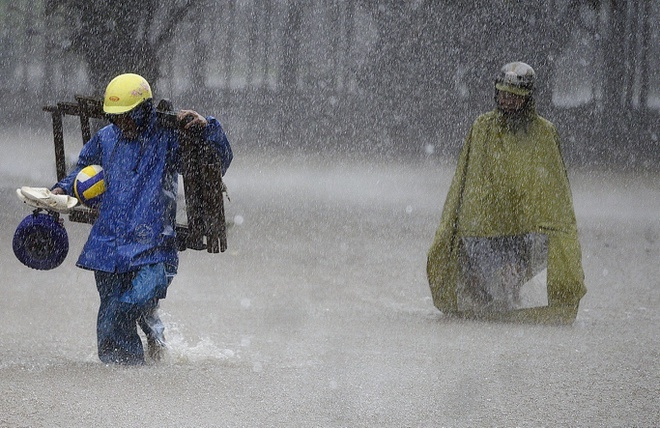 Người dân di chuyển khó khăn trong mưa bão. (Ảnh: VNExpress).