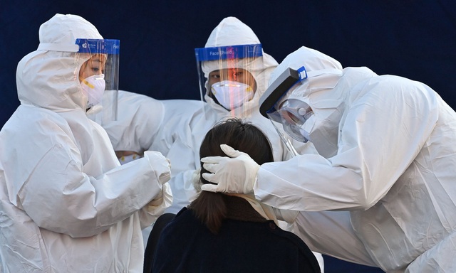 Các nhân viên y tế lấy mẫu xét nghiệm Covid-19 bên ngoài ga tàu ở Seoul ngày 14/12. (Ảnh: AFP)