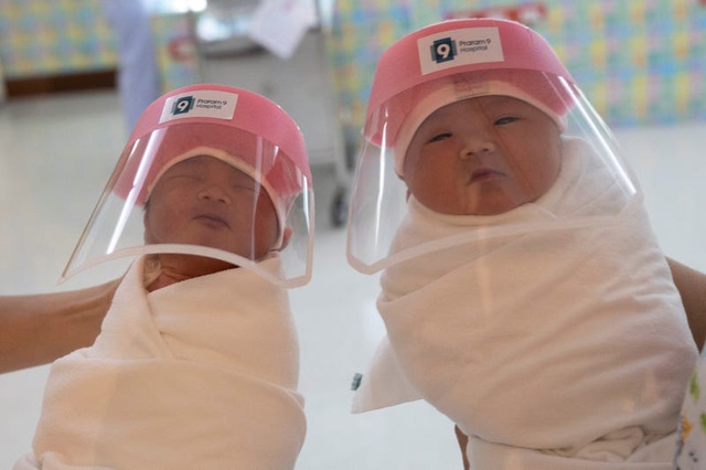 Hai em bé sơ sinh Thái Lan đang đeo tấm chắn giọt bắn trong đợt dịch.