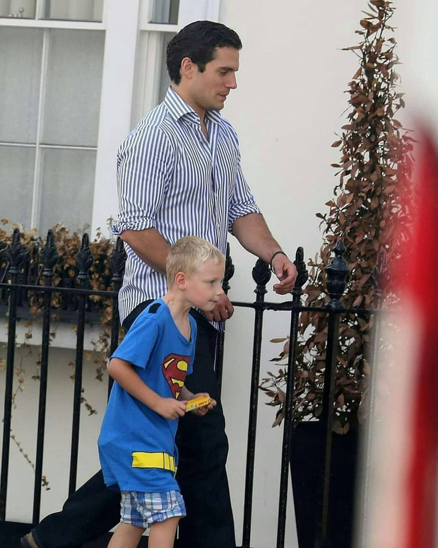 Henry Cavill tay trong tay với đứa cháu 7 tuổi mặc một chiếc áo sơ mi polo có biểu tượng Superman trên đó.