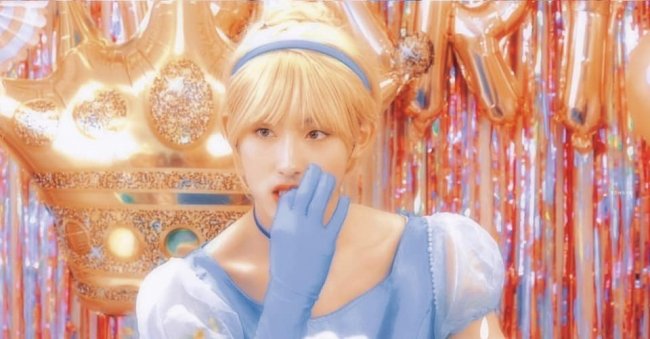 Nam idol hóa thân vào một nhân vật công chúa với chiếc đầm voan xanh, nơ cài, găng tay cùng tông.
