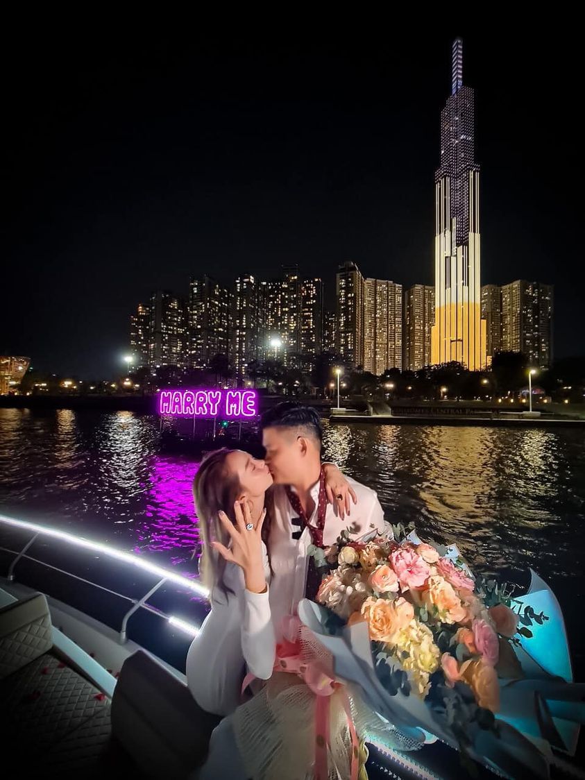 Minh Hằng ôm hôn bạn trai ngọt ngào trong khung cảnh lãng mạn trên du thuyền, xa xa là dòng chữ 'marry me' đầy công phu và chiếc nhẫn kim cương lớn được đeo trên tay nữ diễn viên.  