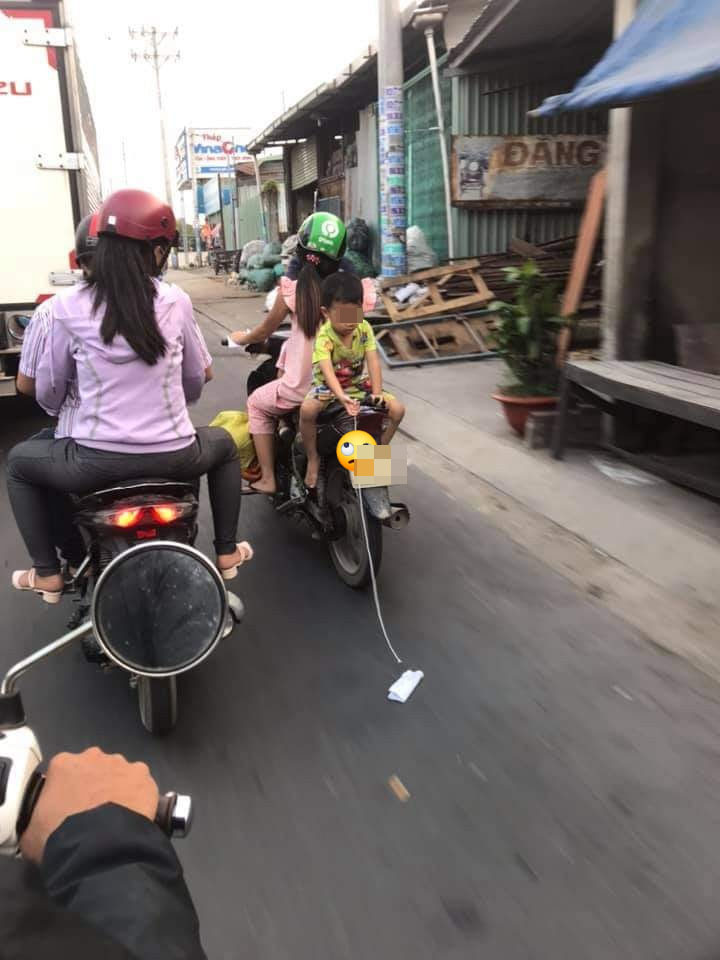 Người mẹ chở con nhỏ đi xe máy, để con ngồi ngược sau yên xe vô tư chơi đùa - Ảnh 2