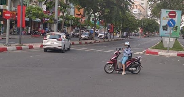 Cô gái dừng xe máy giữa đường đứng bấm điện thoại như