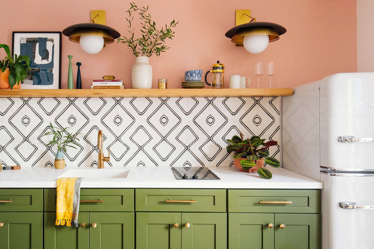 Khu vực nấu nướng với bức tường sơn màu hồng kết hợp màu xanh ô liu của tủ bếp như được phân chia bởi backsplash trắng mang họa tiết hình học cho cái nhìn thoáng đãng và không kém phần hiện đại.