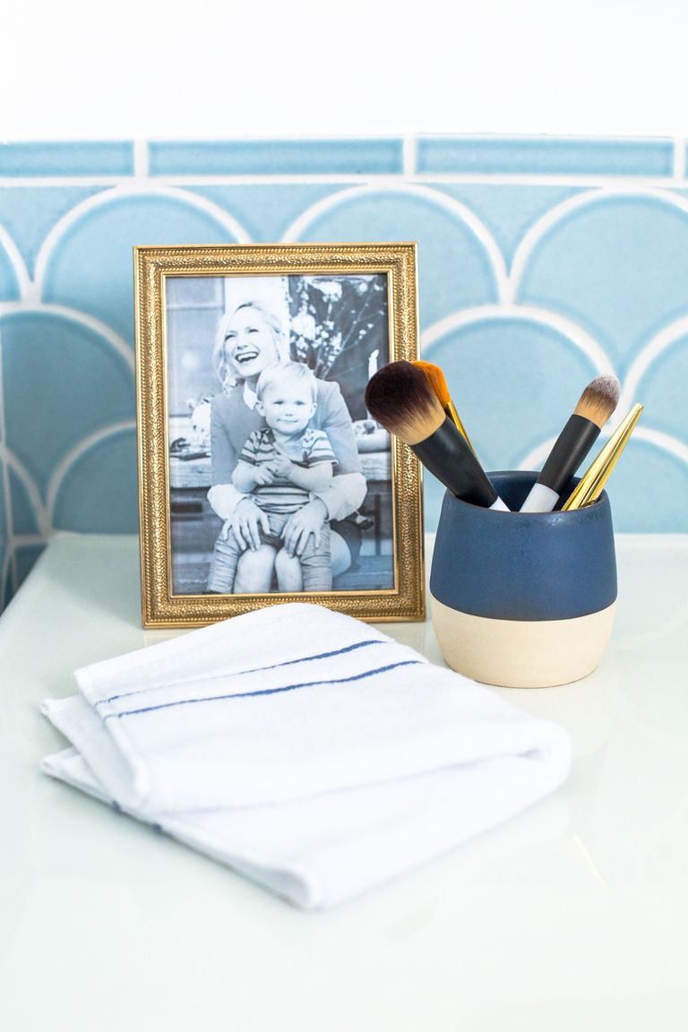 Khu vực trên bồn rửa tay được trang trí bằng một khung ảnh nhỏ có hình Emily và cậu con trai kháu khỉnh. Lọ đựng dụng cụ trang điểm bằng gốm cũng rất hài hòa với gam màu xanh lam đậm và hồng phấn.