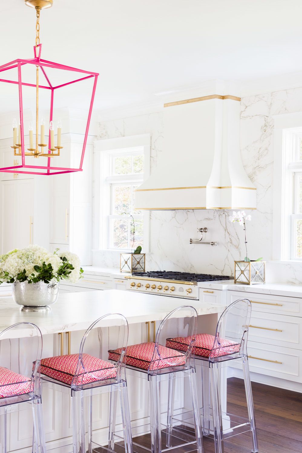 Giữa một phòng bếp lựa chọn tông màu trắng làm chủ đạo thì một chút sắc hồng từ đèn treo ấn tượng cho đến những chiếc đệm trên ghế ngồi trong suốt cũng khiến chúng trở nên vô cùng nổi bật.
