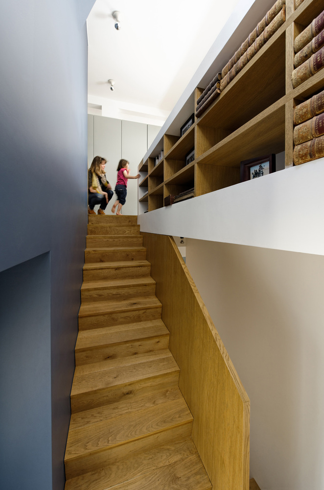 Cầu thang chuyển tiếp lên tầng trên là những ngăn lưu trữ gỗ để tranh ảnh hay bộ sưu tập sách.