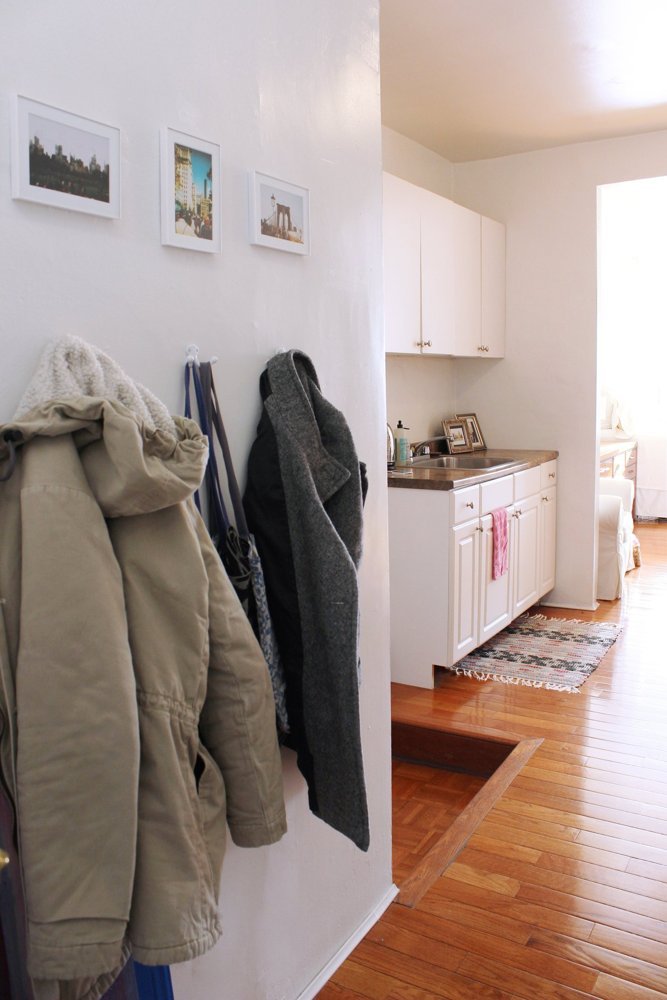 Lối ra vào căn hộ được tận dụng bề mặt tường để treo quần áo.