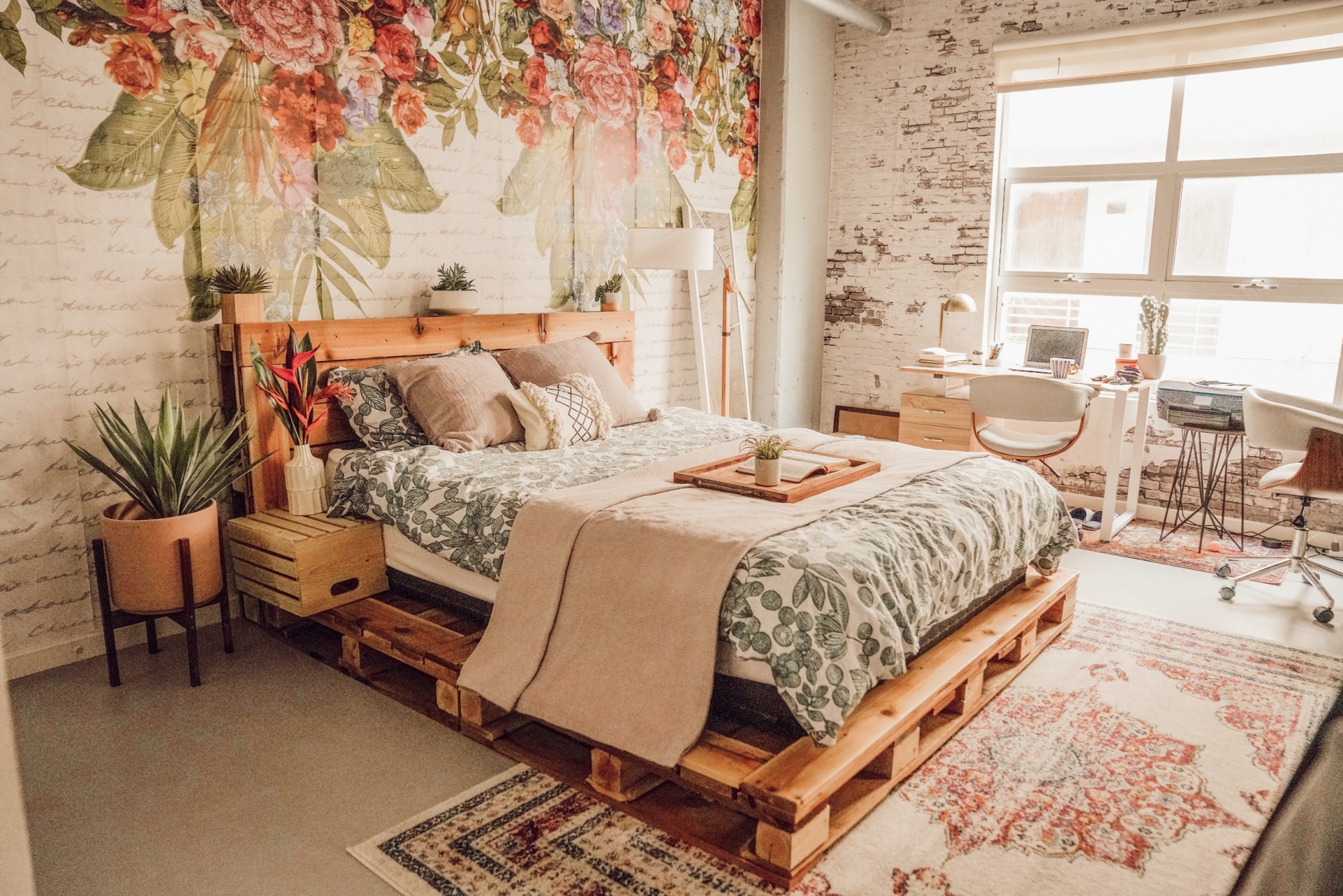 Đẹp nhẹ nhàng và lãng mạn là những gì có thể miêu tả về phòng ngủ này. Chiếc giường gỗ pallet mộc mạc với phần đầu giường được trang trí bởi những chậu cảnh tươi xanh kết hợp giấy dán tường hoa lá như mang cả khu vườn nhỏ vào phòng.