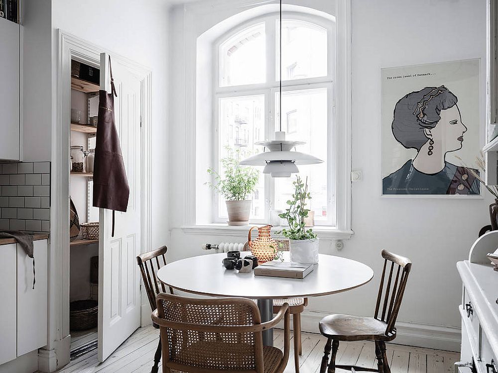 Một phòng ăn nhỏ ngay trong phòng bếp, bên ô cửa sổ đầy nắng ấm. Chiếc bàn tròn đơn giản kết hợp hai mẫu ghế xếp đặt đối xứng: Ghế mây tre đan có tay vịn và ghế gỗ cho cái nhìn linh hoạt.