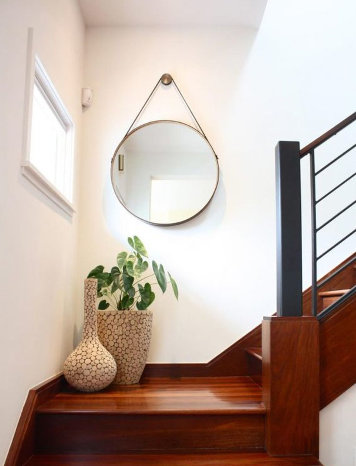 Bạn có thể treo một tấm gương to tròn trên tường, nơi chuyển tiếp giữa cầu thang.