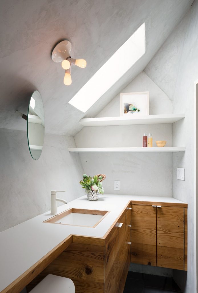 Phòng tắm tận dụng ô cửa nhỏ trên mái nhà để thêm phần thoáng đãng dù diện tích khá chật hẹp.