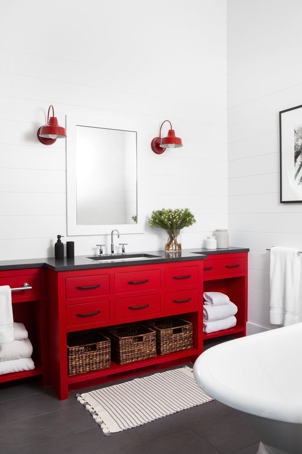 Với tông màu trắng chủ đạo, chiếc tủ sơn đỏ bỗng rực rỡ cả một góc phòng tắm. Bộ đèn chiếu sáng gắn tường đối xứng màu đỏ là điểm cộng hoàn hảo cho khu vực này.