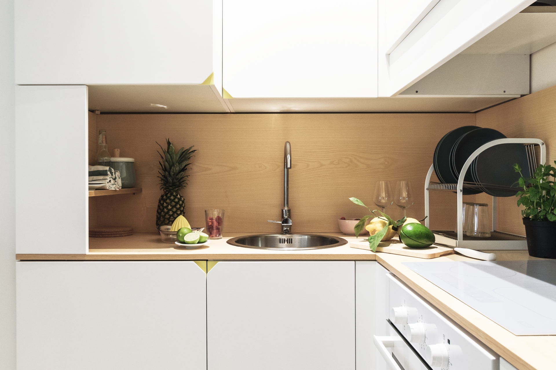 Khu vực bếp nổi bật với hệ tủ lưu trữ màu trắng và backsplash ốp gỗ sáng màu.
