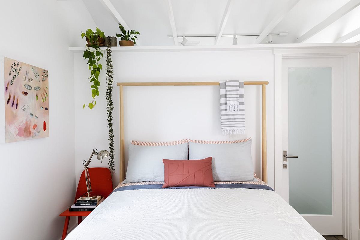 Chiếc giường gỗ được thiết kế cực kỳ đơn giản nhưng tiện lợi với phần đầu giường có thể kết hợp làm giá treo khăn hay phụ kiện. Những bức tranh trừu tượng cũng được sử dụng để làm điểm nhấn cho bức tường bớt đơn điệu, trống trải.