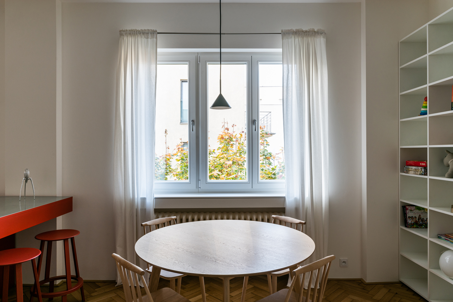 Bộ bàn ăn được bố trí ở cạnh vị trí cửa sổ để có thể tận hưởng tối đa nguồn ánh sáng tự nhiên, kết hợp với rèm che màu trắng mỏng nhẹ và chiếc đèn thả trần đồng bộ với quầy bar mini.