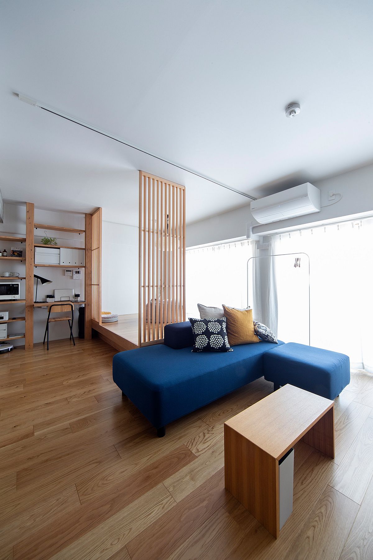 Đối với những ai yêu thích phong cách Minimalism thì phòng khách này sẽ khiến họ yêu mến từ cái nhìn đầu tiên. Chiếc sofa tối giản có thể tách thành hai phần linh hoạt cùng gam màu xanh dương đậm nổi bật trên nền sàn gỗ mộc mạc.