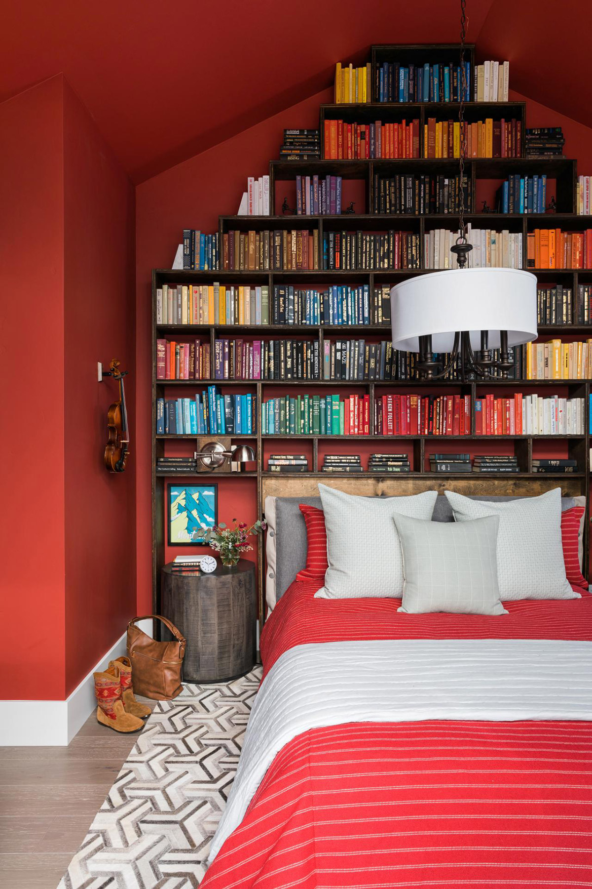 Đây quả thực là căn phòng hoàn hảo cho những ai yêu đọc sách. Toàn bộ tường được sơn màu đỏ kết hợp với bộ ga gối vô cùng ấm áp. Phần đầu giường thiết kế kệ sách mở như một thư viện tại gia cực kỳ thú vị.