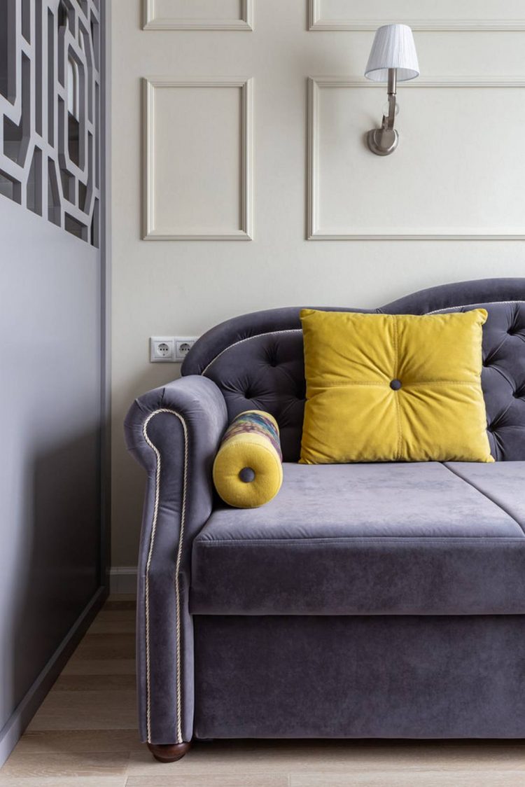 Những chiếc gối tựa màu vàng mù tạt nổi bật trên nền ghế sofa màu tím cho cái nhìn bắt mắt và trẻ trung, đặc biệt là giữa không gian lựa chọn gam màu trung tính làm chủ đạo.
